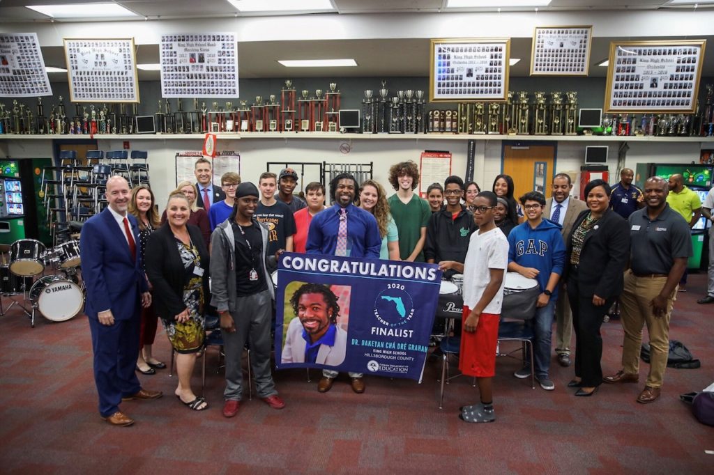 Dr. Dakeyan Graham poses with his students and a sign announcing he is a finalist for Teacher of the Year.