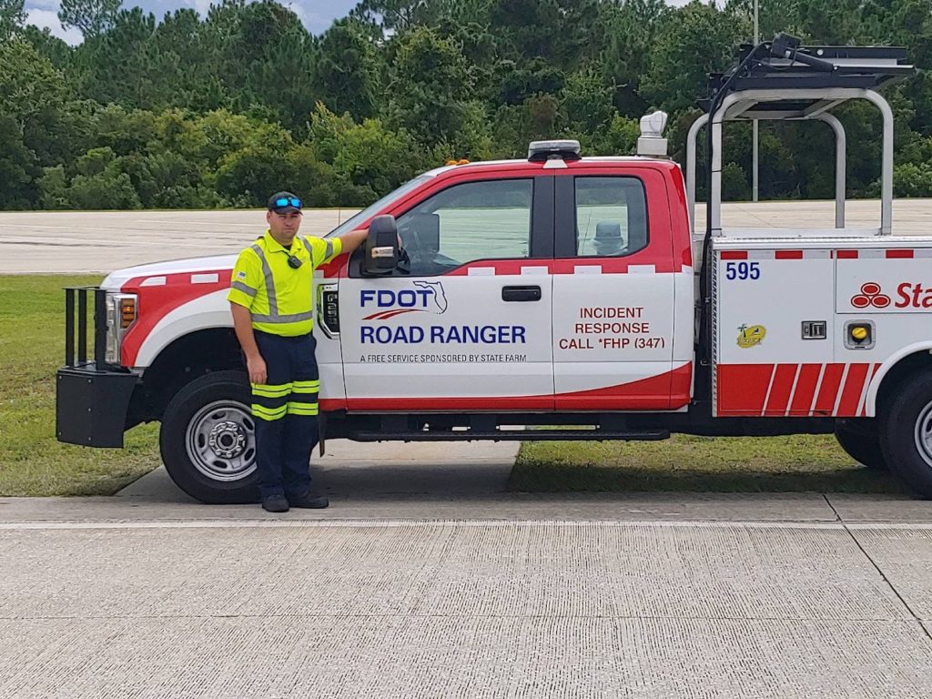 Photograph of Christopher Thomas standing in front of his FDOT truck.