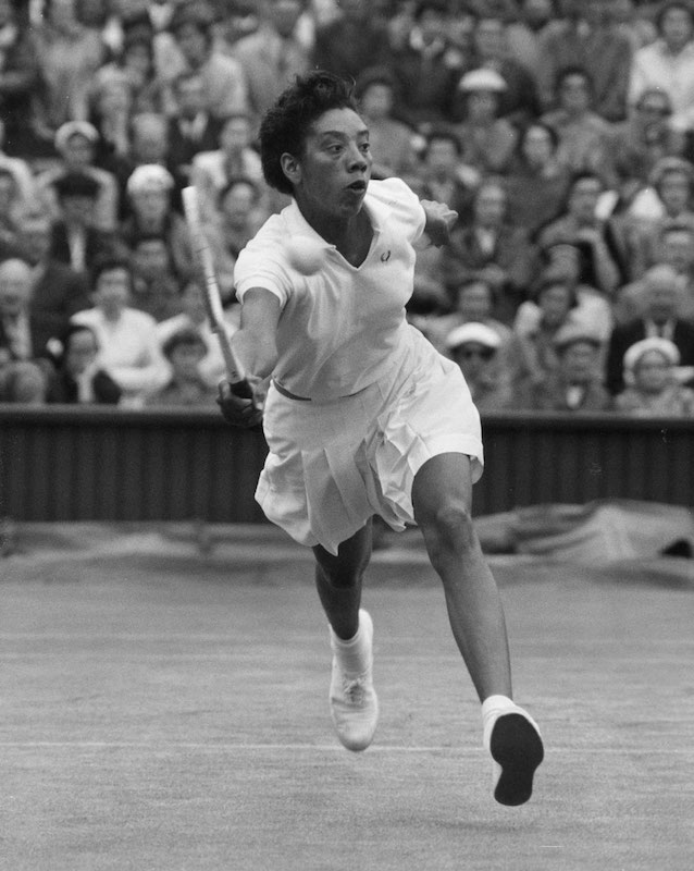 Black and white action photograph of Althea Gibson on the court.