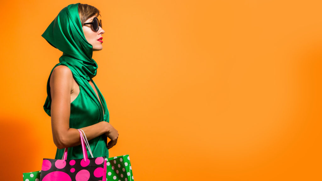 Young happy summer shopping woman with shopping bags isolated over bright orange background