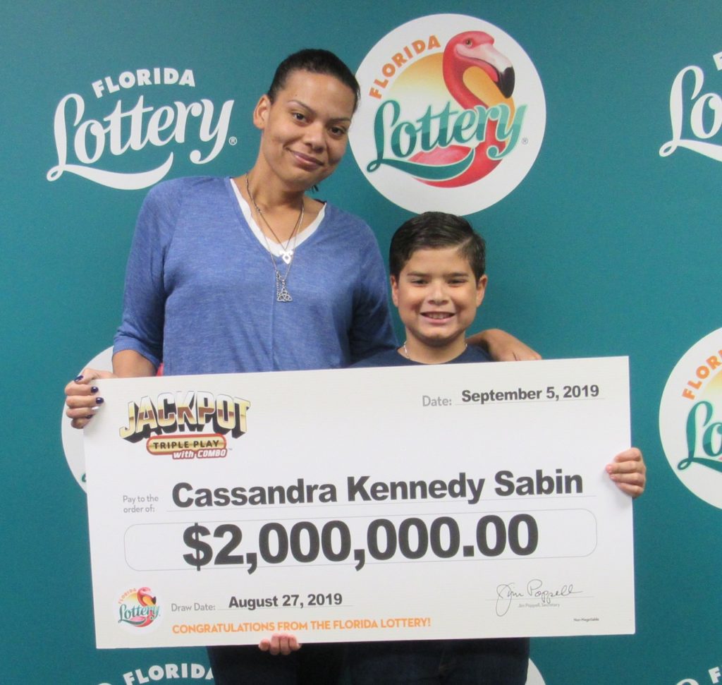 Cassandra Kennedy Sabin poses with her son and oversized check after claiming a $2 million JACKPOT TRIPLE PLAY jackpot from the August 27, 2019 drawing at Florida Lottery Headquarters.