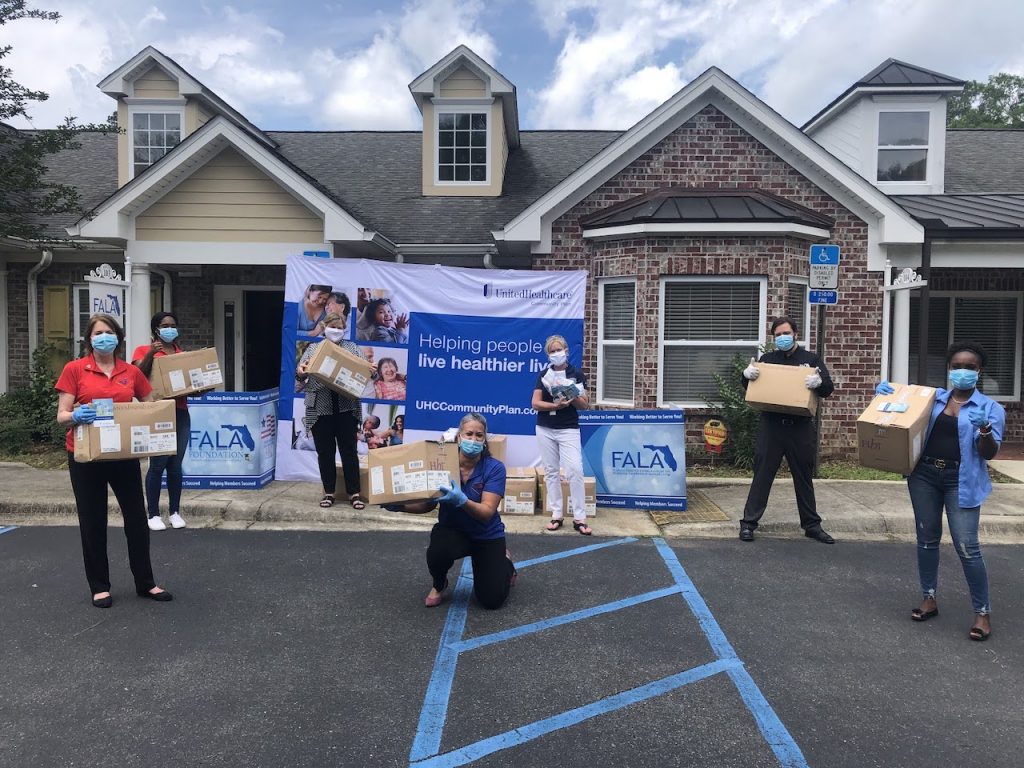 FALA and UnitedHealthcare Community Plan staff members move dozens of boxes containing cloth masks. 