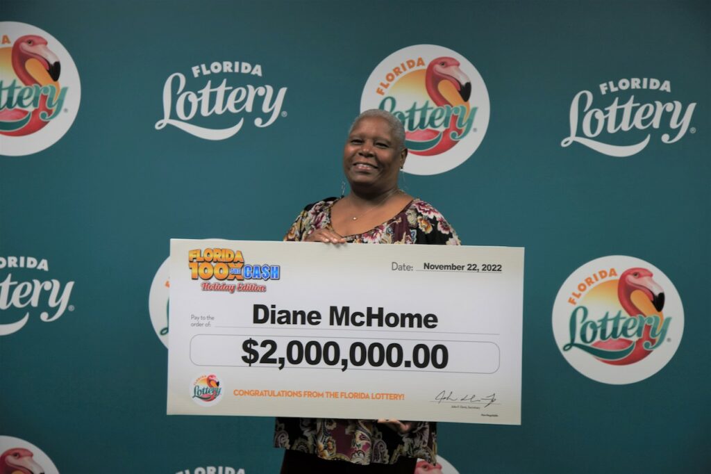Diane McHome poses with oversized check after claiming a $2 million top prize from the 100X THE CASH Scratch-Off game at Florida Lottery Headquarters in Tallahassee.